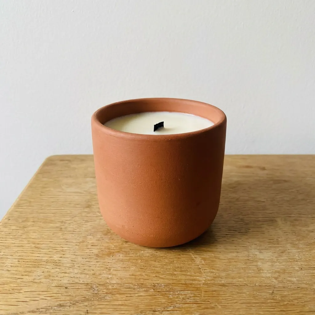 A seller's plain photo: a terracotta candle on a wooden side table.